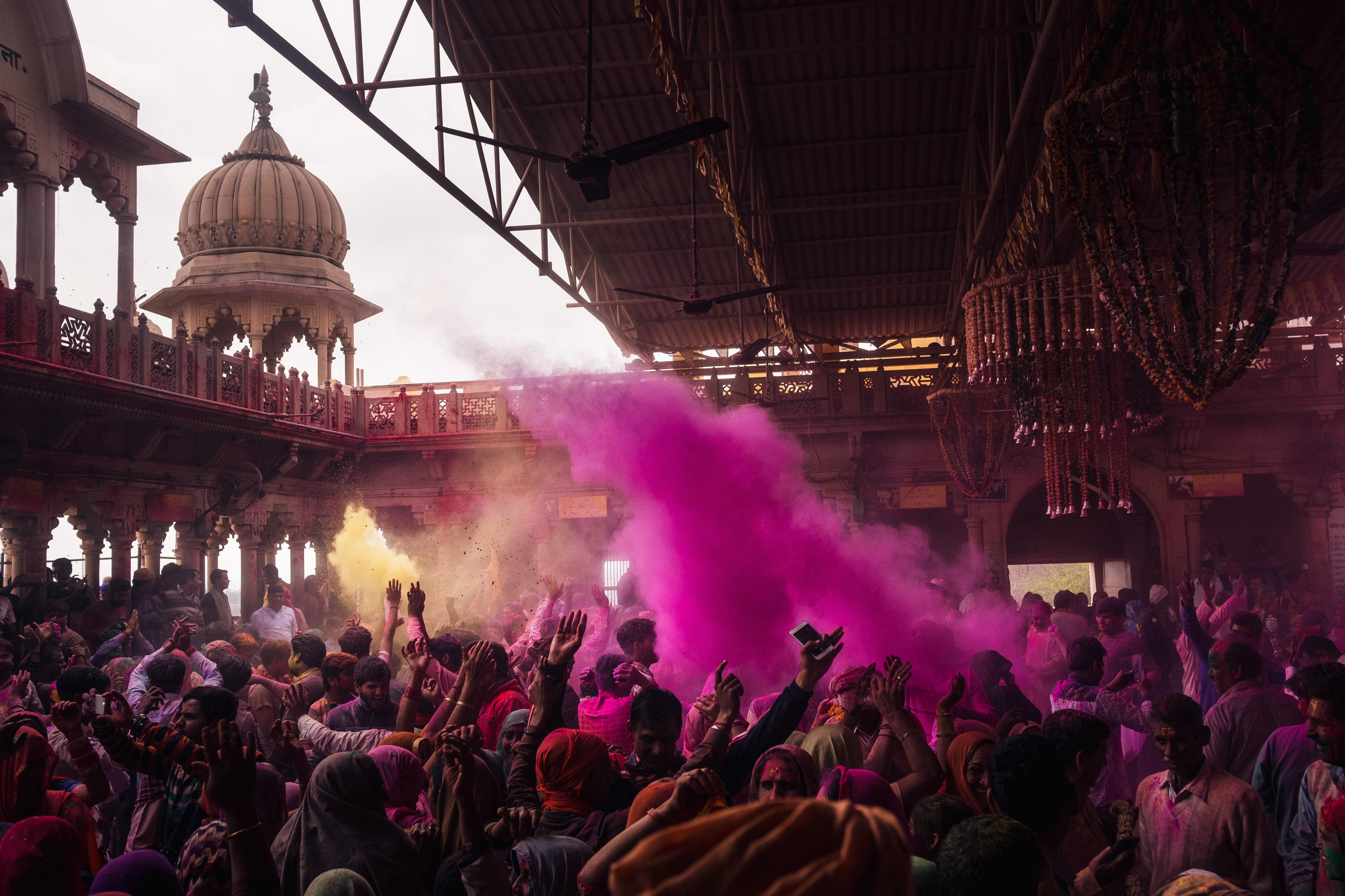 India Street Photography During Holi Festival. pink cloud of smoke rises over the crowd. Images by Jason Vinson