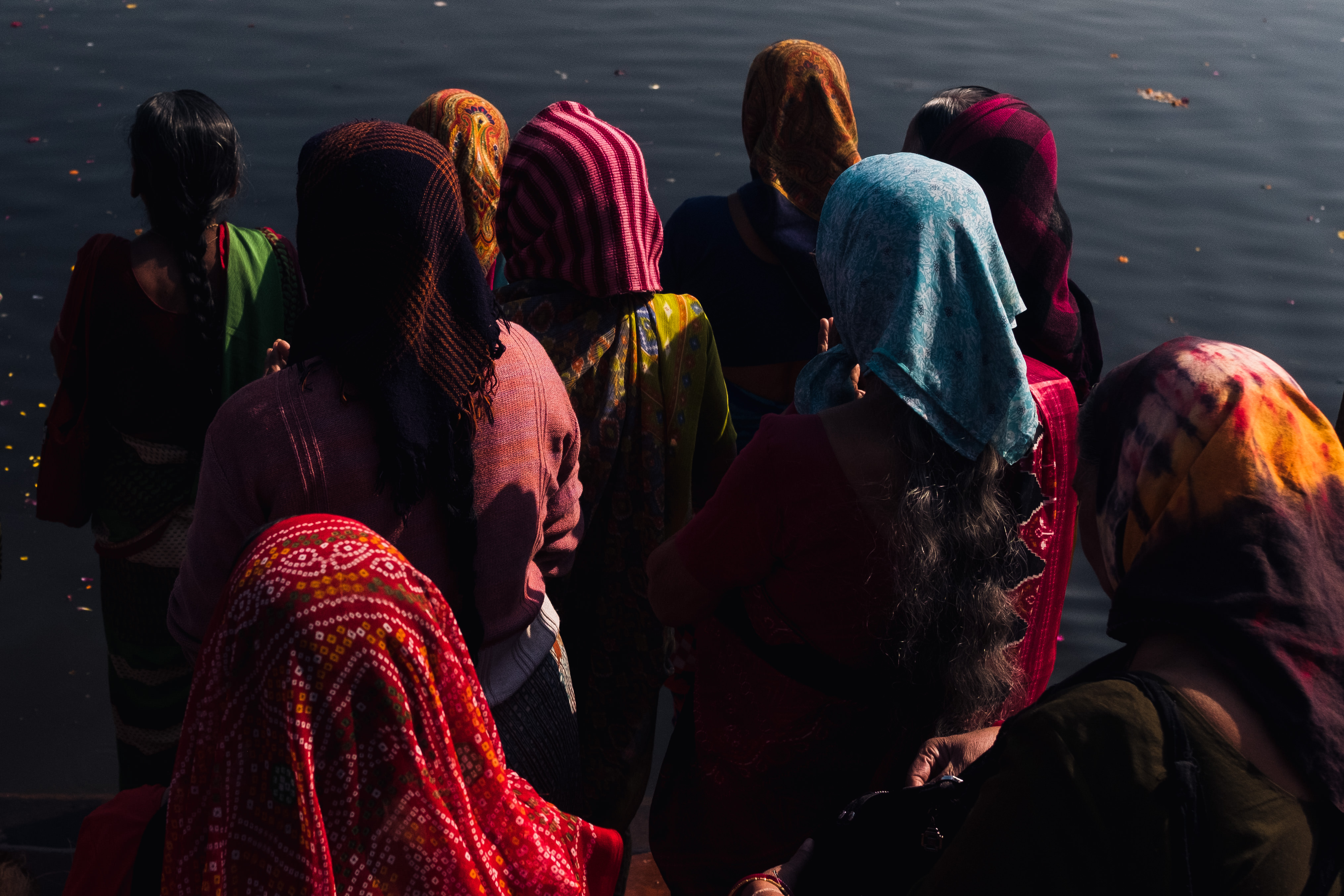 India Street Photography During Holi Festival. ladies stand in front of water praying. Images by Jason Vinson