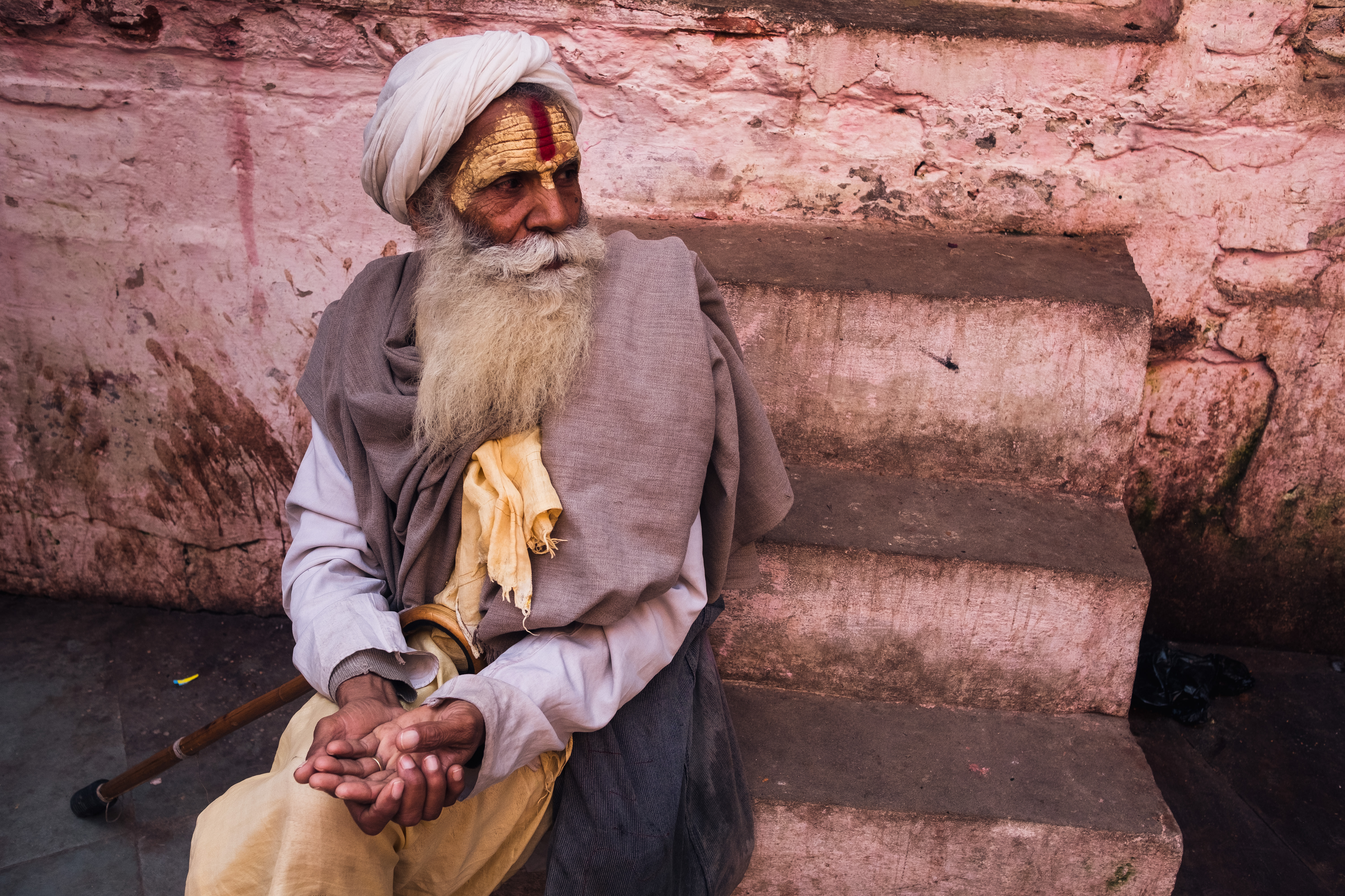 India Street Photography During Holi Festival. Priest sitting in front of wall asking for money. Images by Jason Vinson