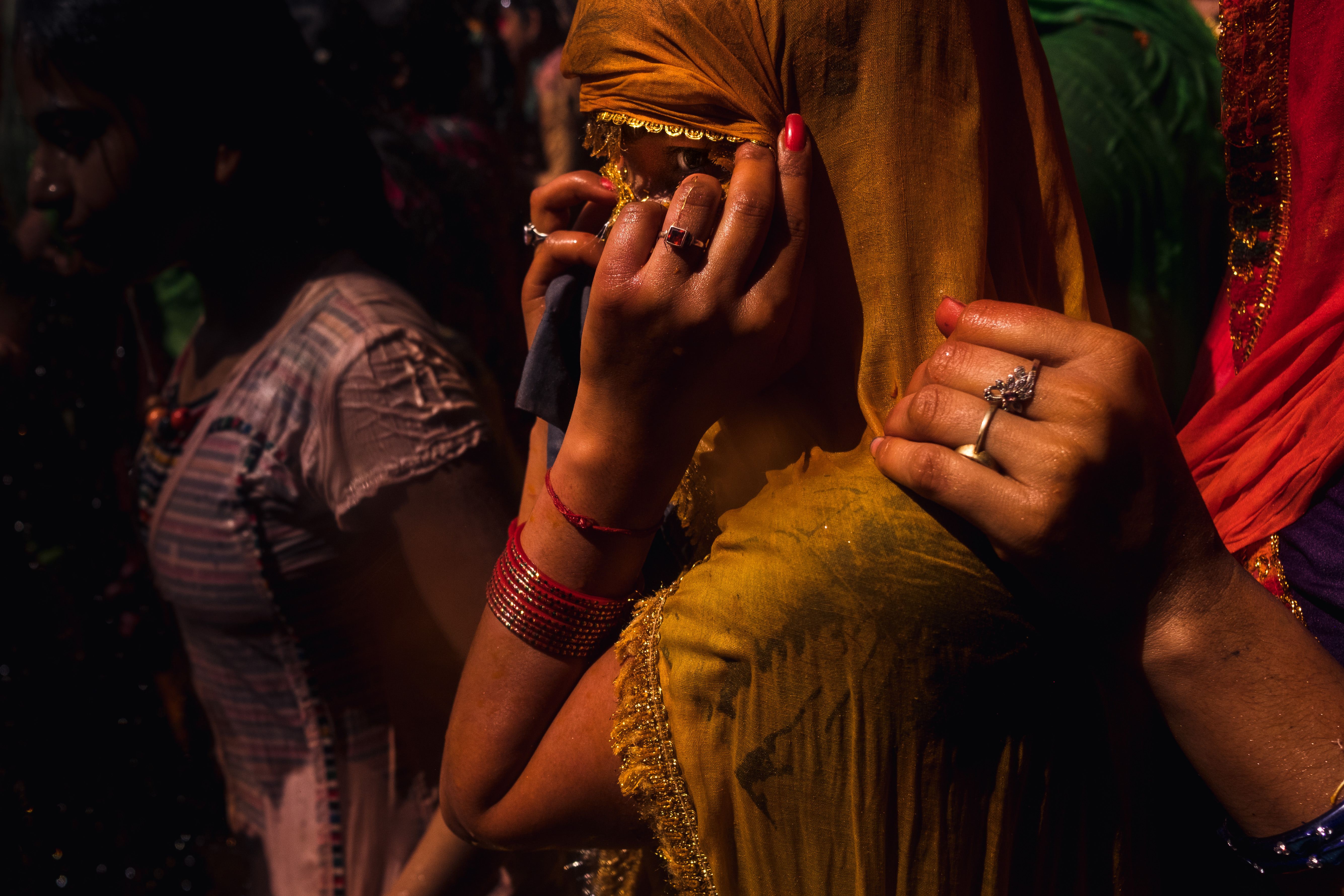 India Street Photography During Holi Festival. woman shields her face as she is comforted by lone hand. Images by Jason Vinson