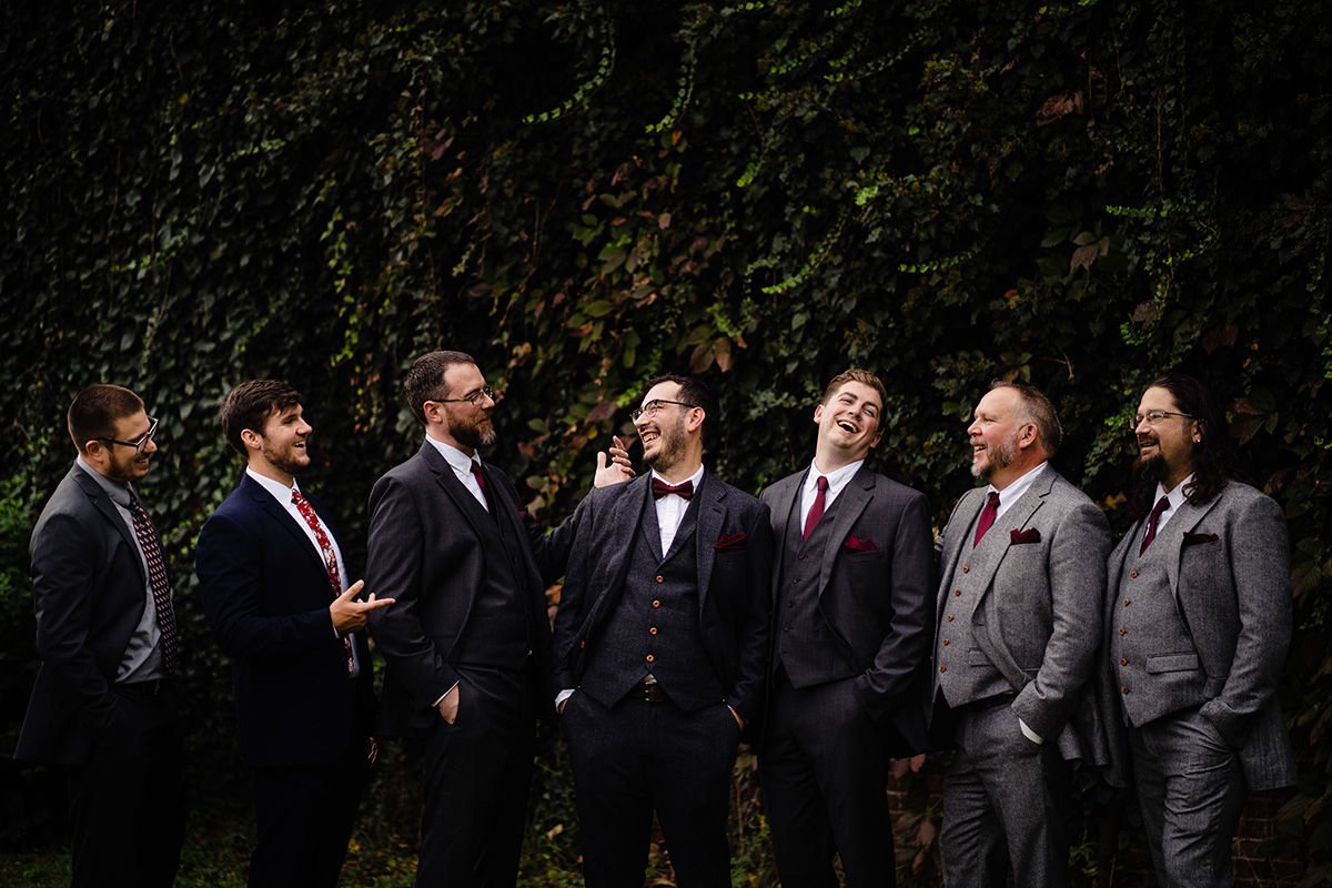 Centerton-Arkansas-Wedding-The-Ravington-NWA-Wedding-groomsmen-laughing-in-front-of-ivy-wall