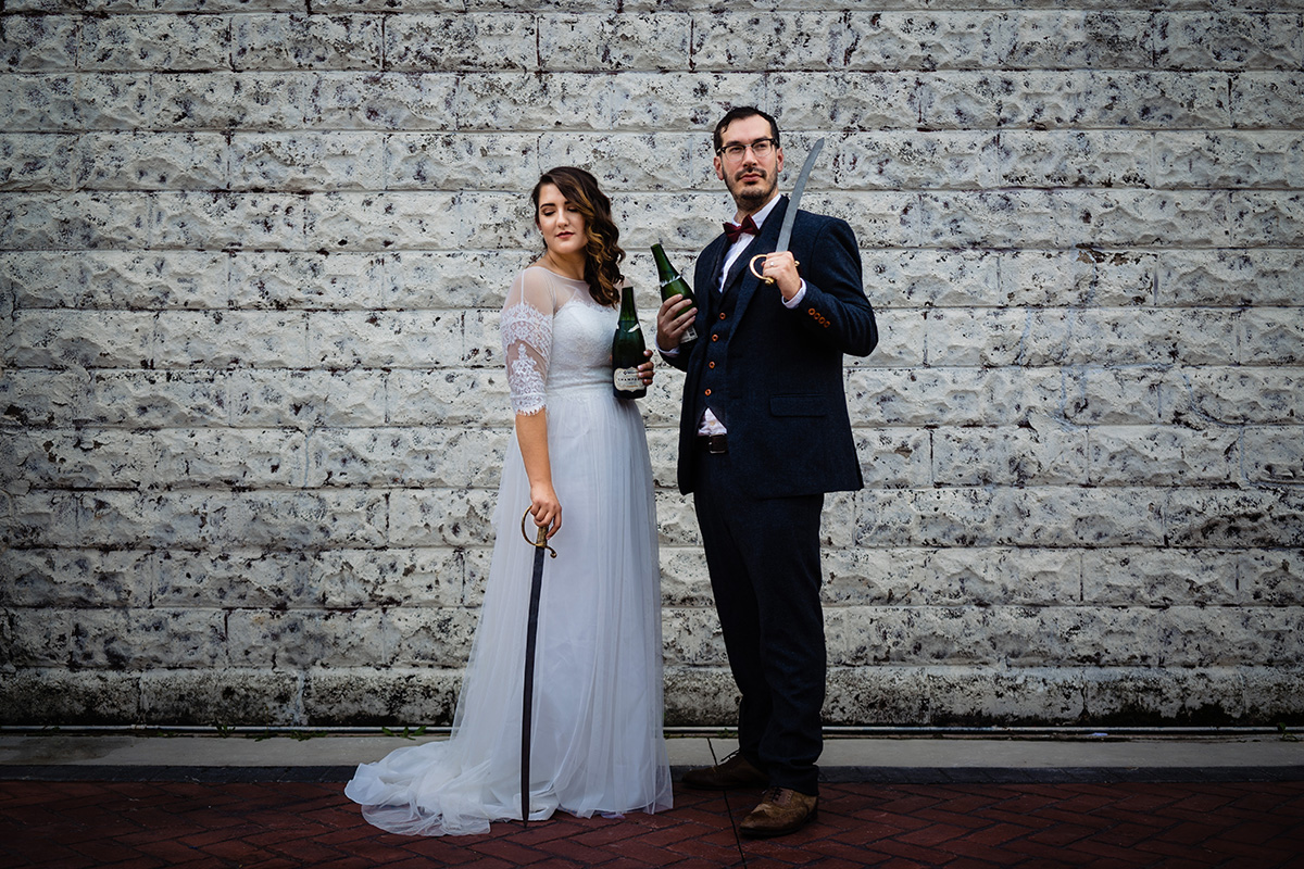 Centerton-Arkansas-Wedding-The-Ravington-NWA-Wedding-bride-and-groom-pose-with-swards-and-champagne-bottles