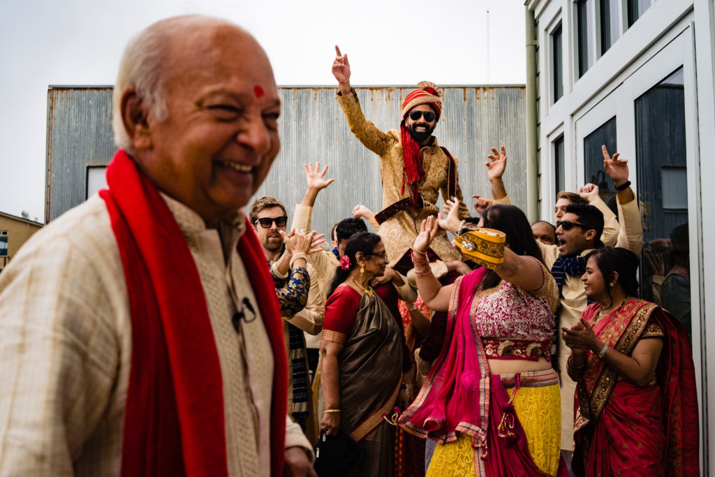 Northwest Arkansas Indian Wedding Photography Vinson Images- groom dancing during baraat as priest laughs 