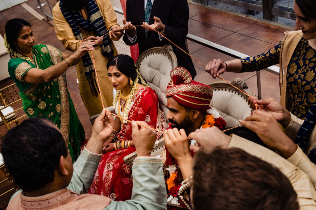Northwest Arkansas Indian Wedding Photography Vinson Images-  family wraps string around bride and groom 