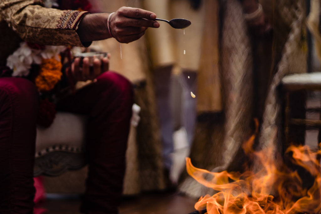 Northwest Arkansas Indian Wedding Photography Vinson Images- groom places things into fire as part of ceremony 
