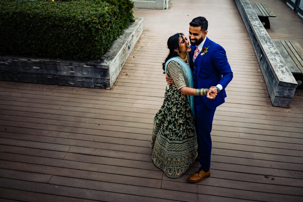 Northwest Arkansas Indian Wedding Photography Vinson Images- bride and groom laugh and dance on Monterrey California boardwalk 