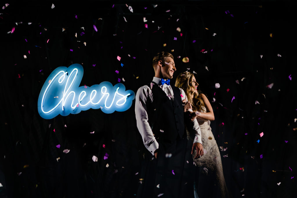 Walton Arts center wedding by Vinson Images - Northwest Arkansas Wedding photography - couple laughing in confetti with neon cheers sign