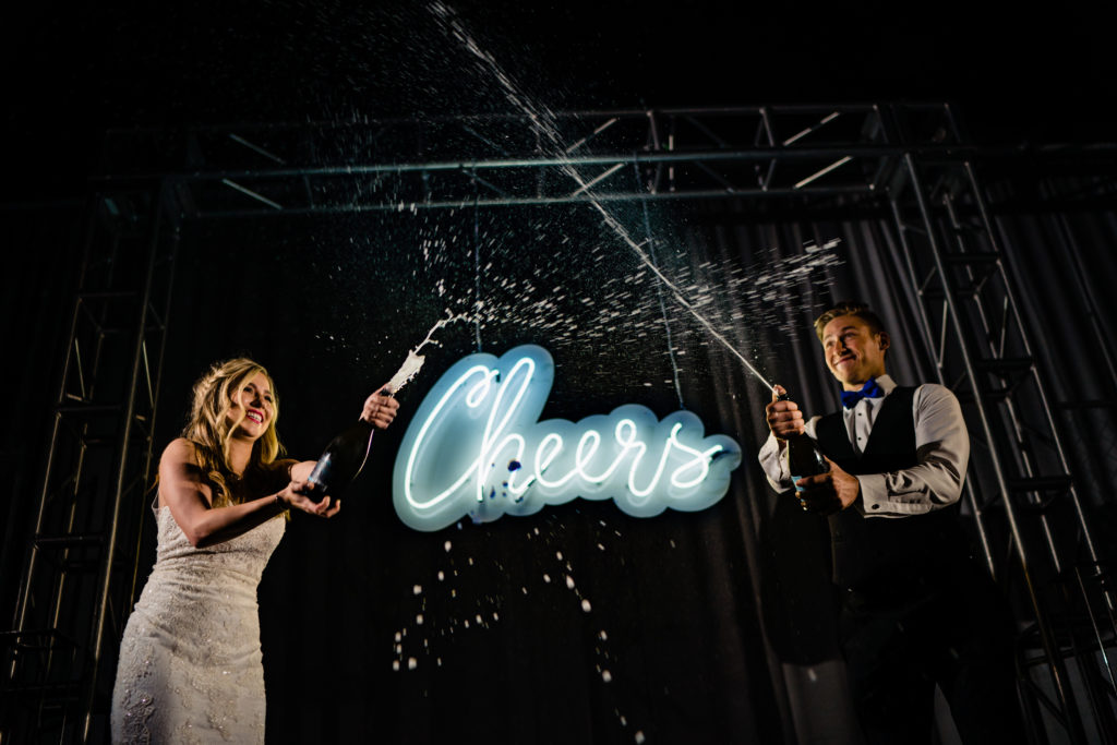 Walton Arts center wedding by Vinson Images - Northwest Arkansas Wedding photography - couple spraying champagne in Starr theater room
