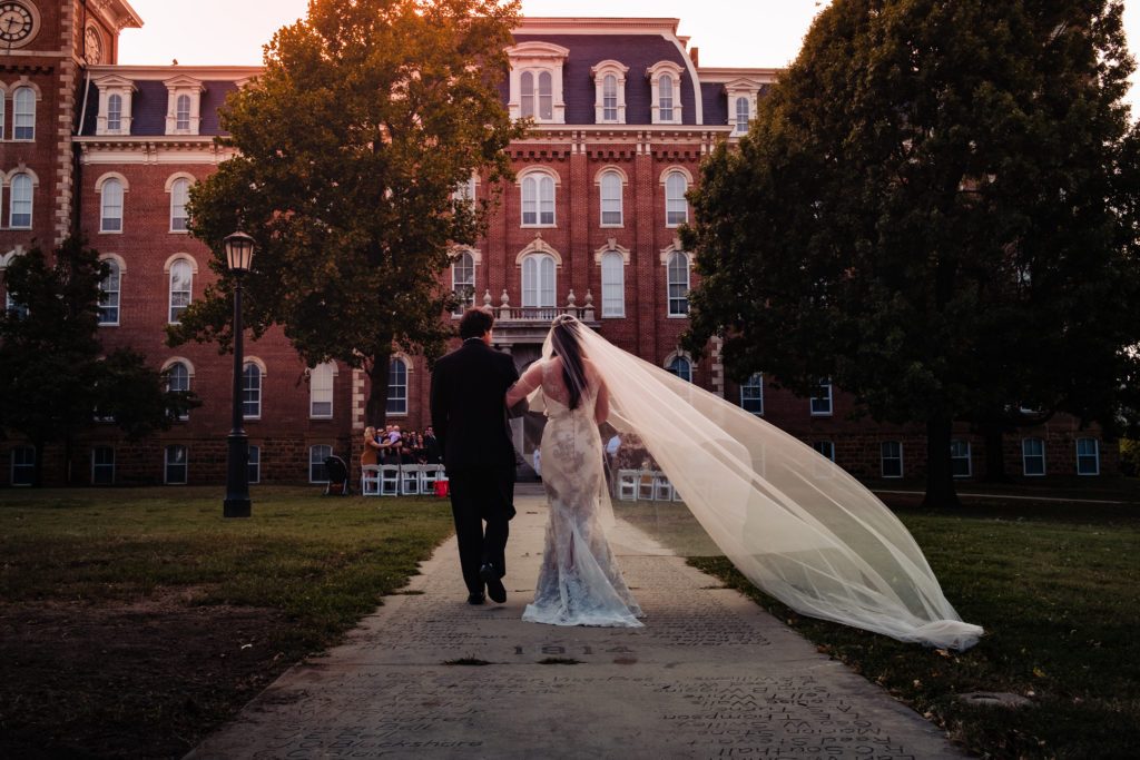 Fayetteville Arkansas Wedding - Old Main Lawn ceremony - bride get lead to wedding as her veil blows in the wind