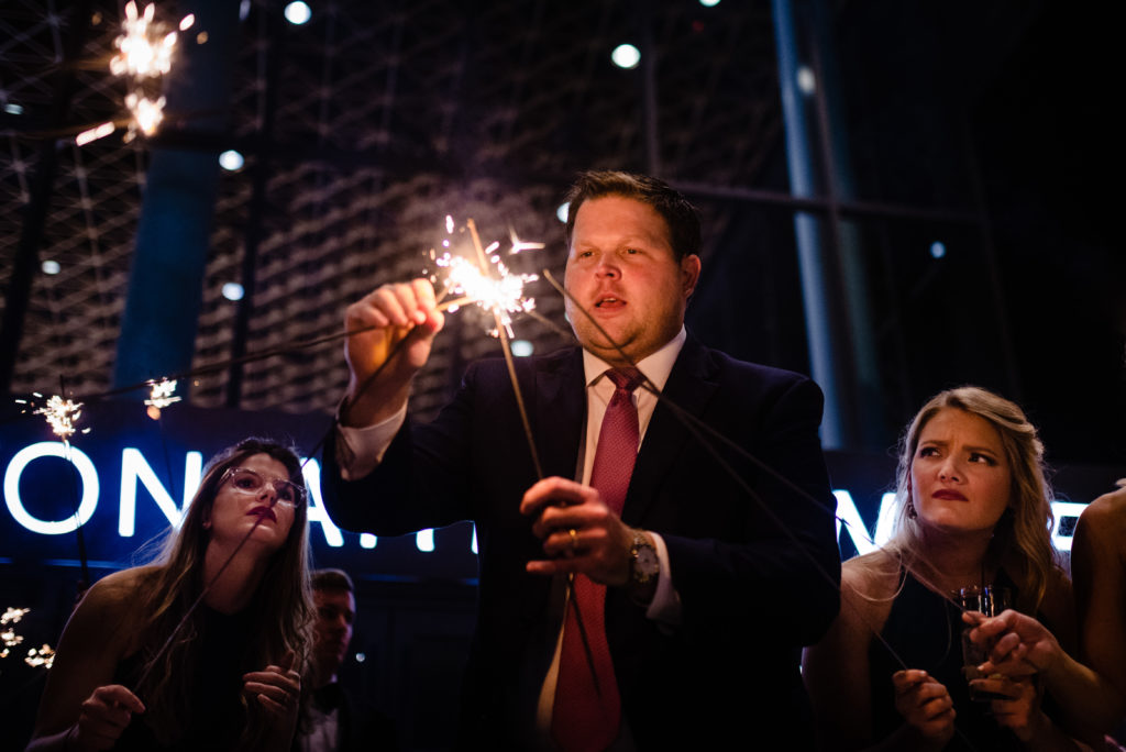 Vinson Images - Walton Arts Center Wedding - guests watch as guy tries to light sparklers
