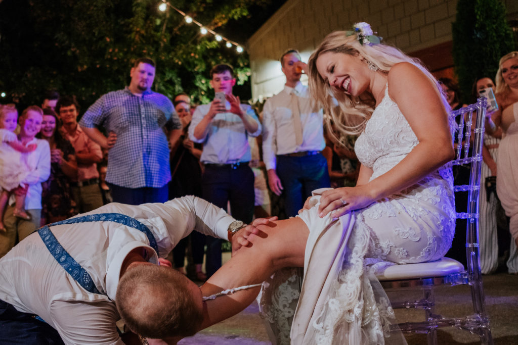 The Stone Chapel At Matt Lane Farms - Fayetteville Arkansas wedding - bride laighs as the groom take garter 