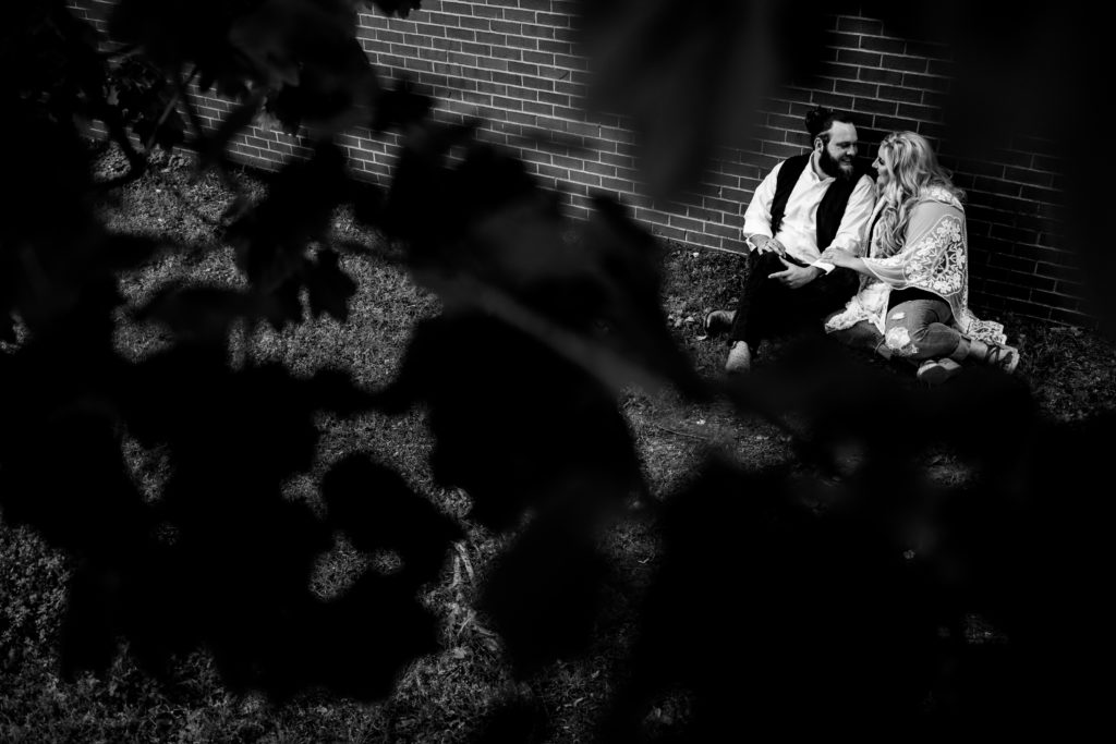 Northwest Arkansas Wedding Photography - Vinson Images - Downtown Rogers Engagement - couple on lawn and brick wall