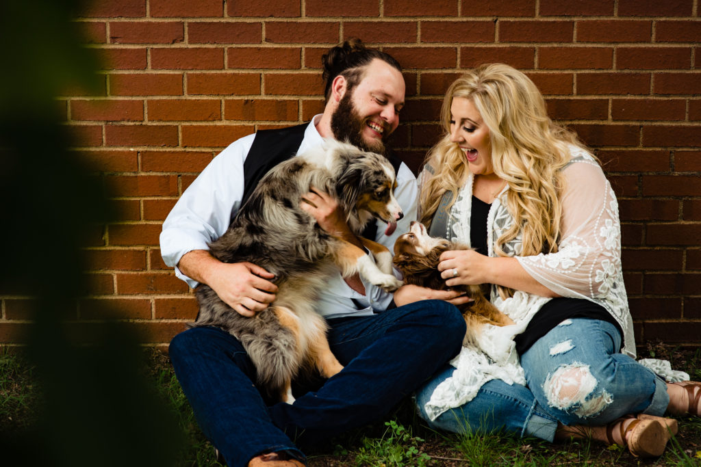 Northwest Arkansas Wedding Photography - Vinson Images - Downtown Rogers Engagement - couple laughing with puppies 
