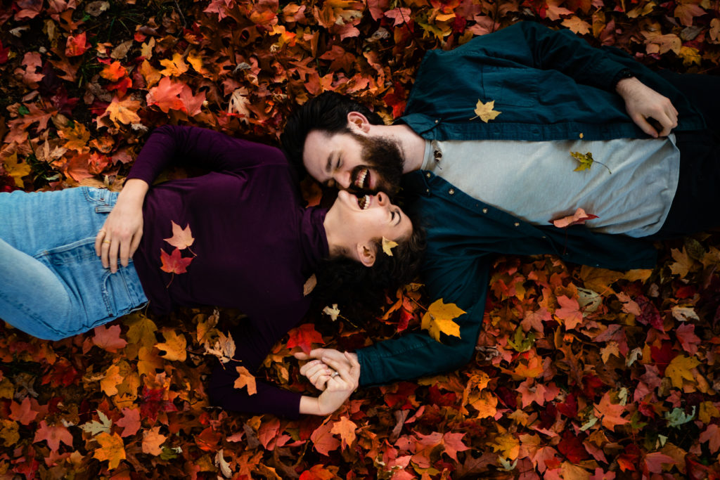 Couple laughs in the fall leaves during a Northwest Arkansas Date night