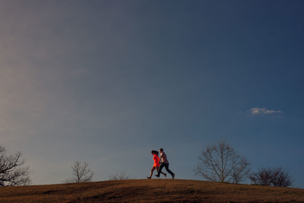 couple runs through the grass during a date night in Rogers Arkansas 