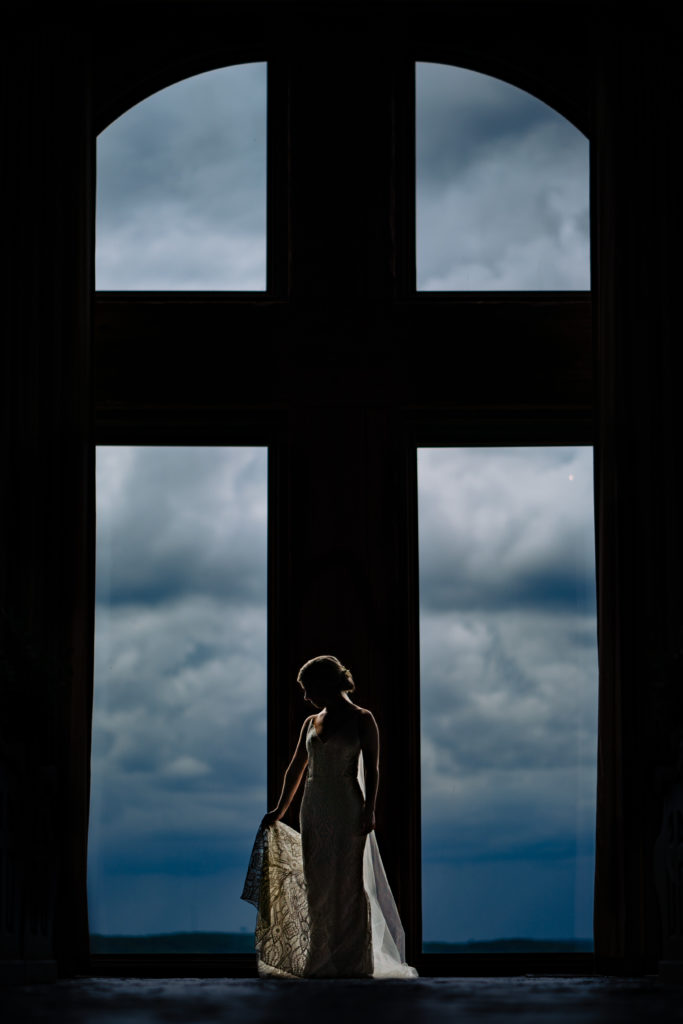 Bride stand in front of large window at chapel of the Ozarks