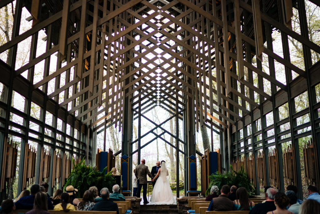 Couple hold hand at the alter of Thorncrown glass chapel 