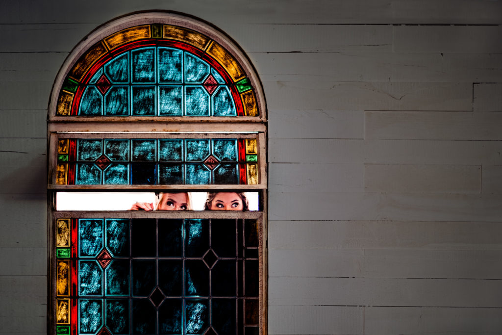 Bride peeks in on wedding ceremony through stained glass window at The Ravington  