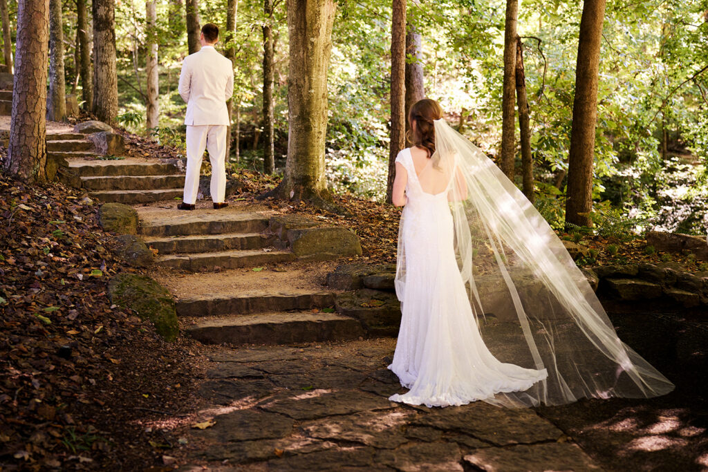 Emotional first look between a bride and groom on the wooded trails of the Crystal Bridges North Forest in Bentonville